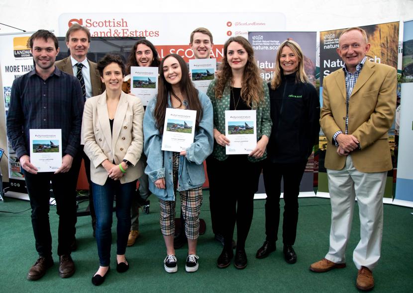Competition winners standing with certificates, alongside NatureScot staff and Mairi Gougeon MSP.