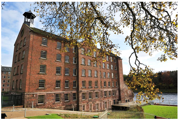 Six storey red brick mill building backing onto the river