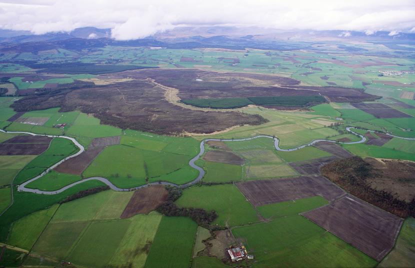 Aerial view of Flanders Moss a raised bog, surrounded by farmland, with a river running through.