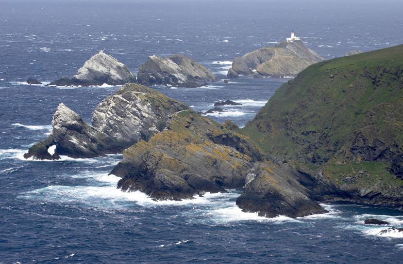 Group of islands in the sea with a lighthouse on the far island.