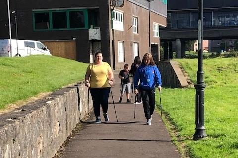 Adults walking on path with nordic walking poles