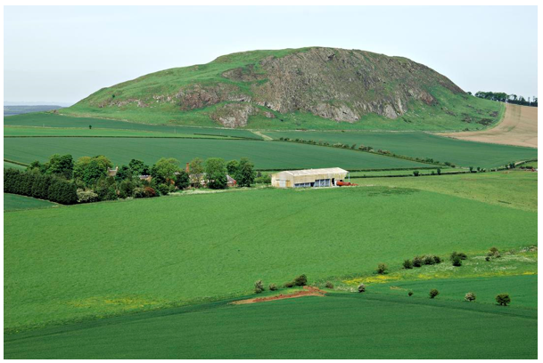 Traprain Law stands out from flat farmland, domed to one side and steeper rocky side to the front.