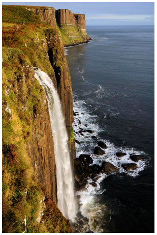 Waterfall descends vertically straight to the sea and the dolerite columns of Kilt Rock are in the background.