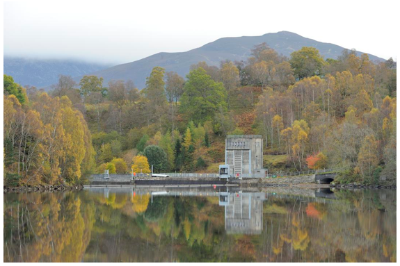 Loch Tummel dam and buildings surrounded by deciduous woodland.