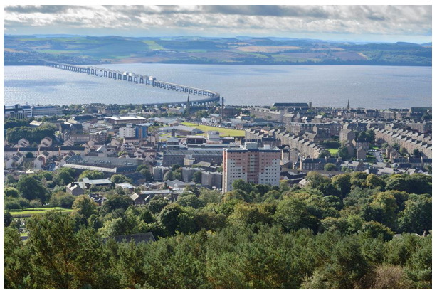 Tay bridge curving away from the city and tower blocks blending with tenements and commercial buildings closer to the river