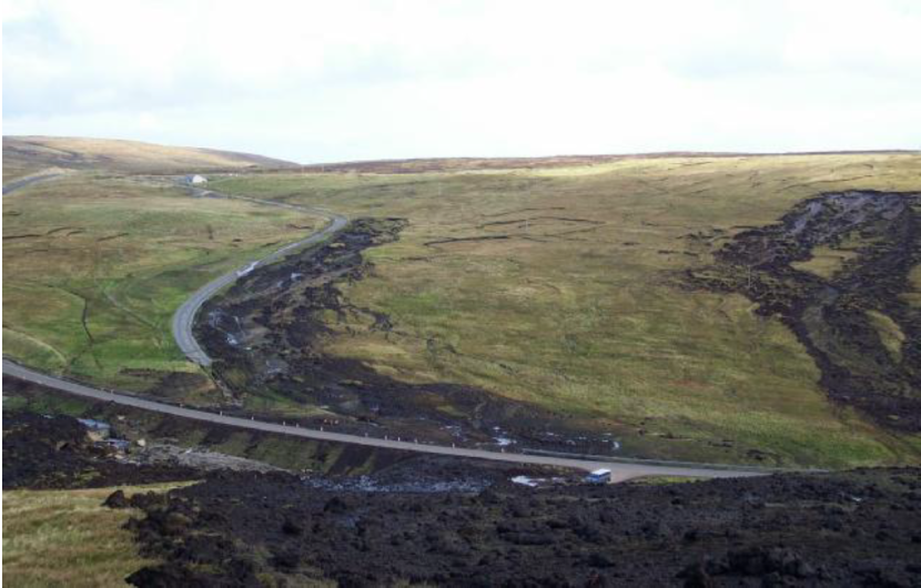 Peat slide impacting road with hill in background