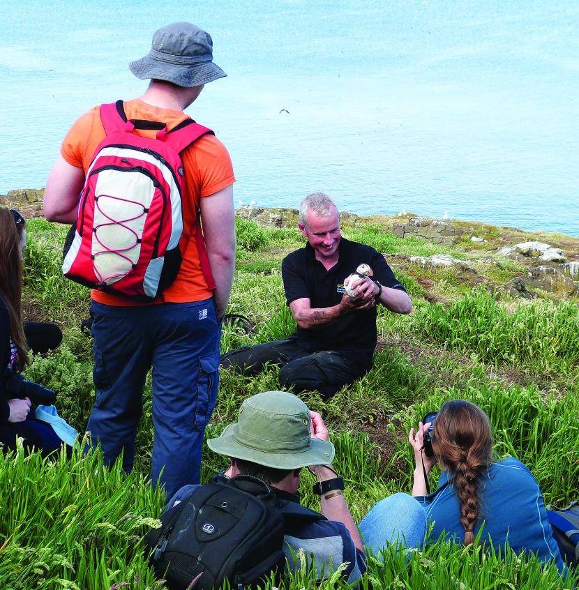 Reserve Manager showing the public a Puffin for scientific purposes.