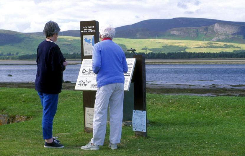 Two visitors reading an interpretation board at Loch Fleet National Nature Reserve. 