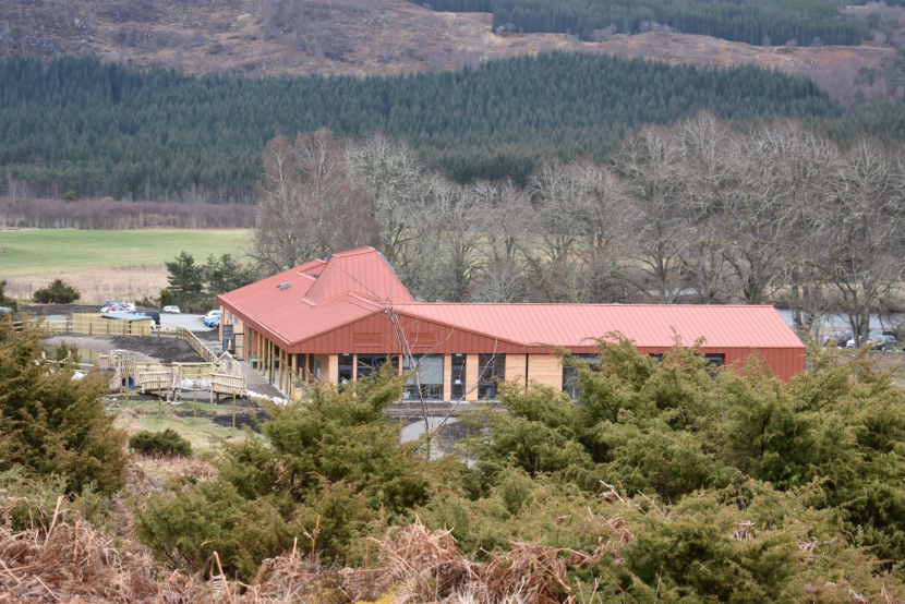 Building with a red roof, surrounded by woodland