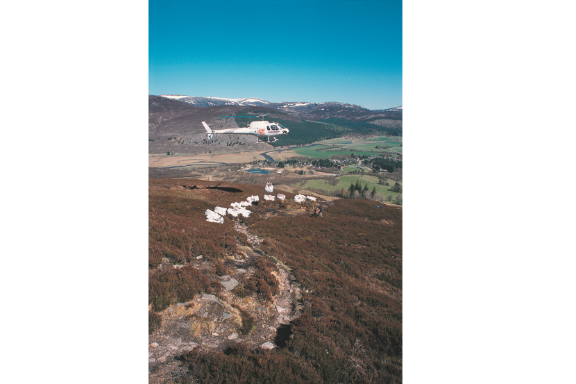 Helicopter transporting materials to site in large heli-bags