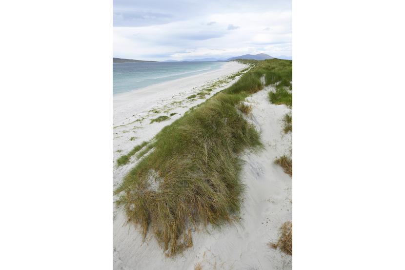 Sand dunes running alongside the shoreline and off into the mountains in the distance