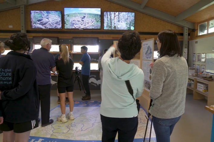 Groups of people looking at interpretation boards, tv sceens and displays.