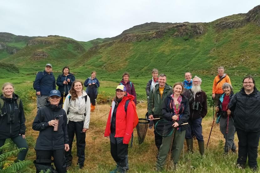 Group of adults in hiking gear, with hills in the background. 