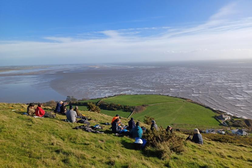 Group sitting on a hill overlooking the sea.