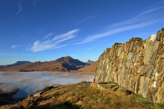 Knockan Crag National Nature Reserve - a view of the reserve wall with a mountain range in the distance.