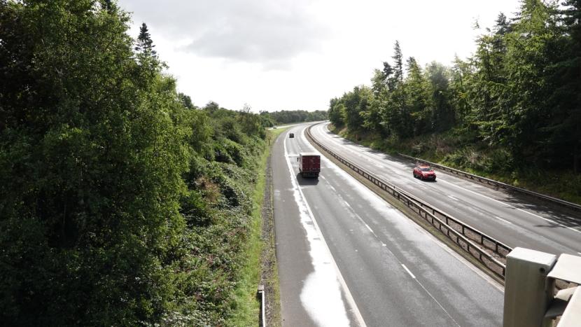 M9 motorway southbound with woodland and scrub abutting closely to narrow 