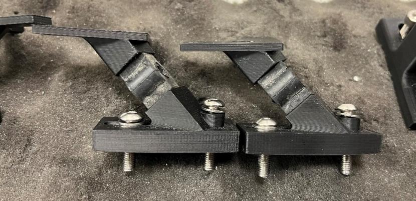 Photo of black rubber mounts between two black plastic fastening plates with bolts in.