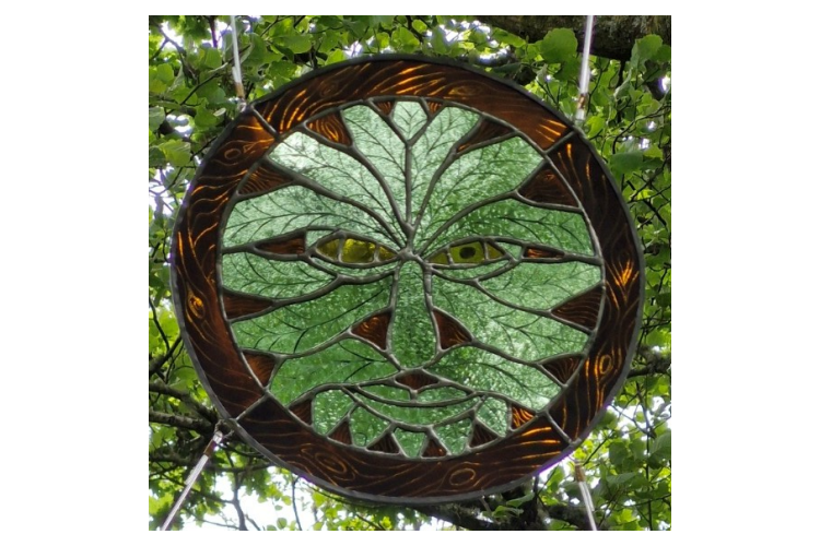 Agnes MacLean - Metal circle showing a face made of leaves, with wood weaving in the background