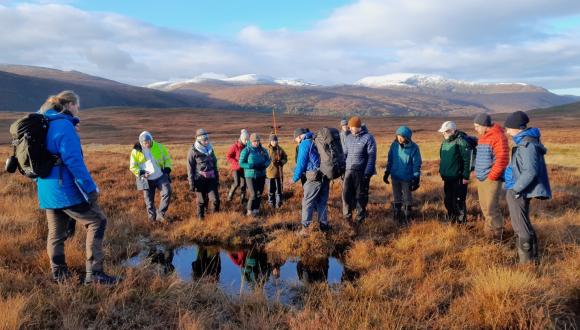 Course leader talking to a group of people in a peatland landscape setting