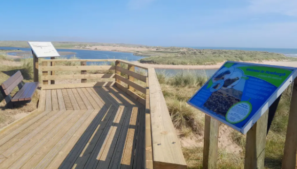 Accessible boardwalk and viewing area overlooking the estuary with the beach and dunes in the background.