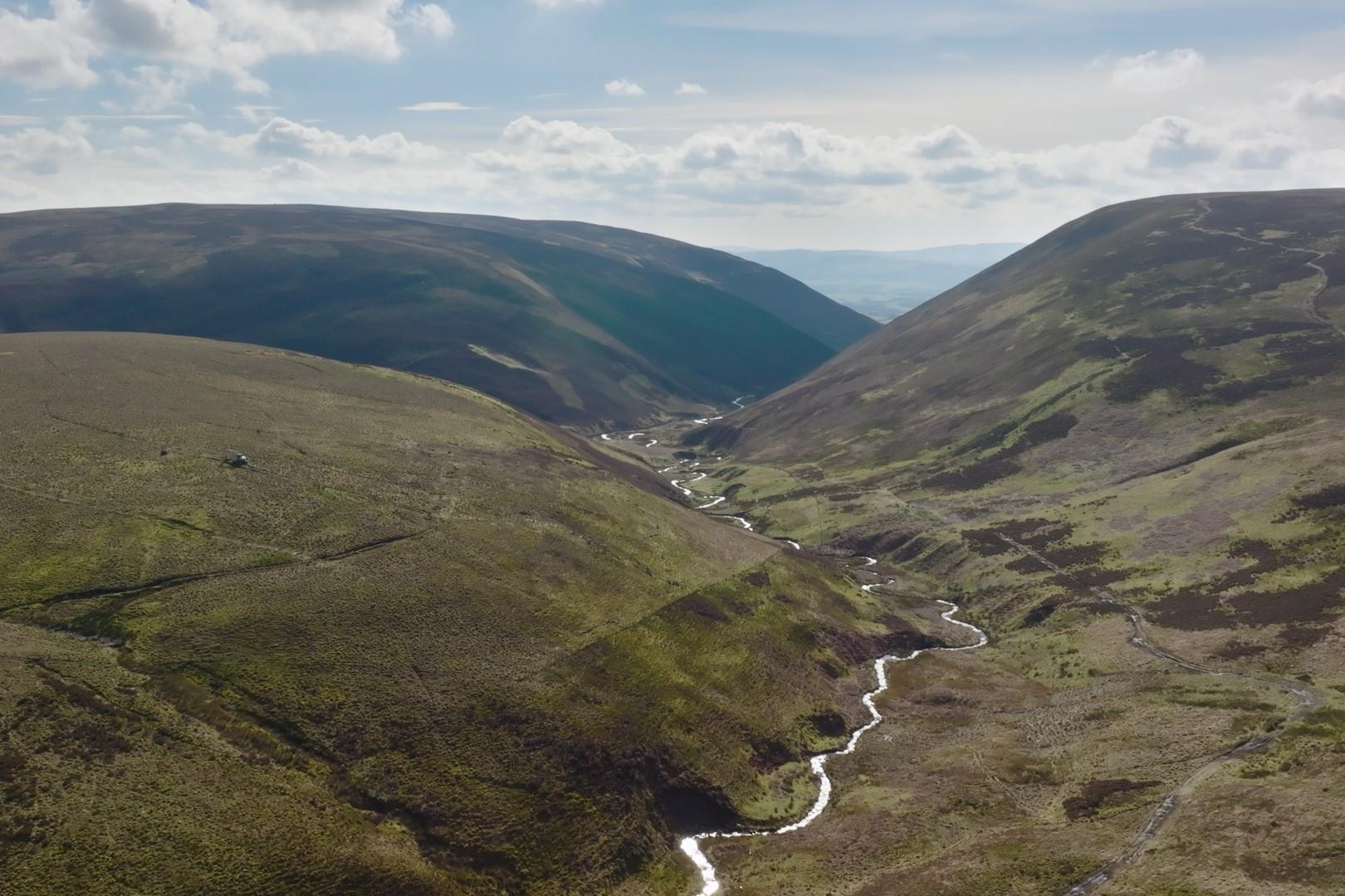Three hills with a river weaving through the middle.