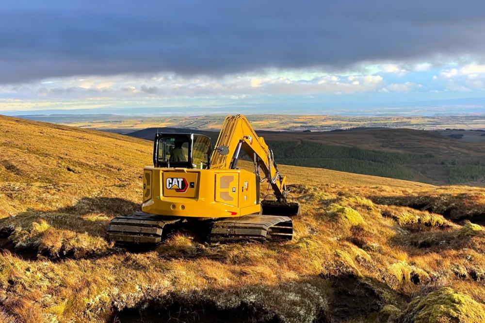 Digger digging up peatland on a hill