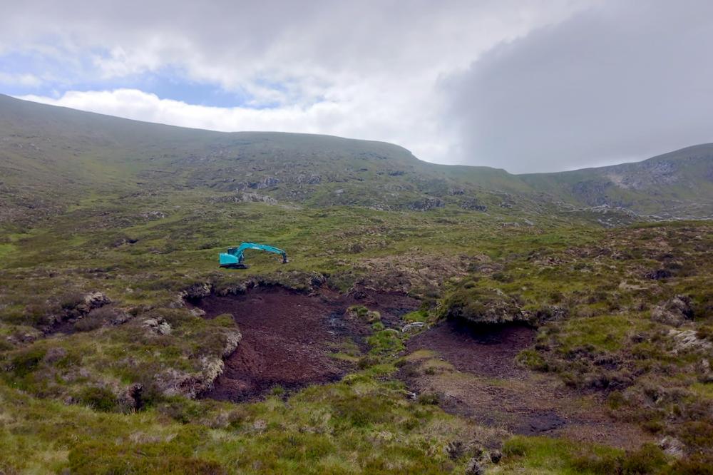 Digger restoring peatland on a hill