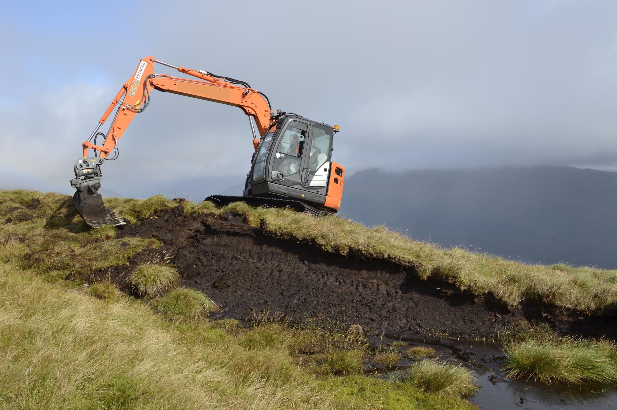 Peatland Action - Digger re-profiling bare peat hag.